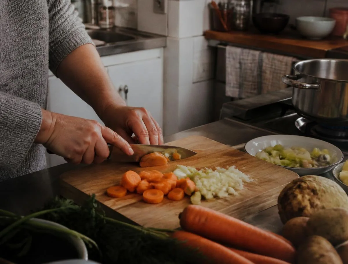 Betreuerin bereitet in der Küche eine frische Mahlzeit zu